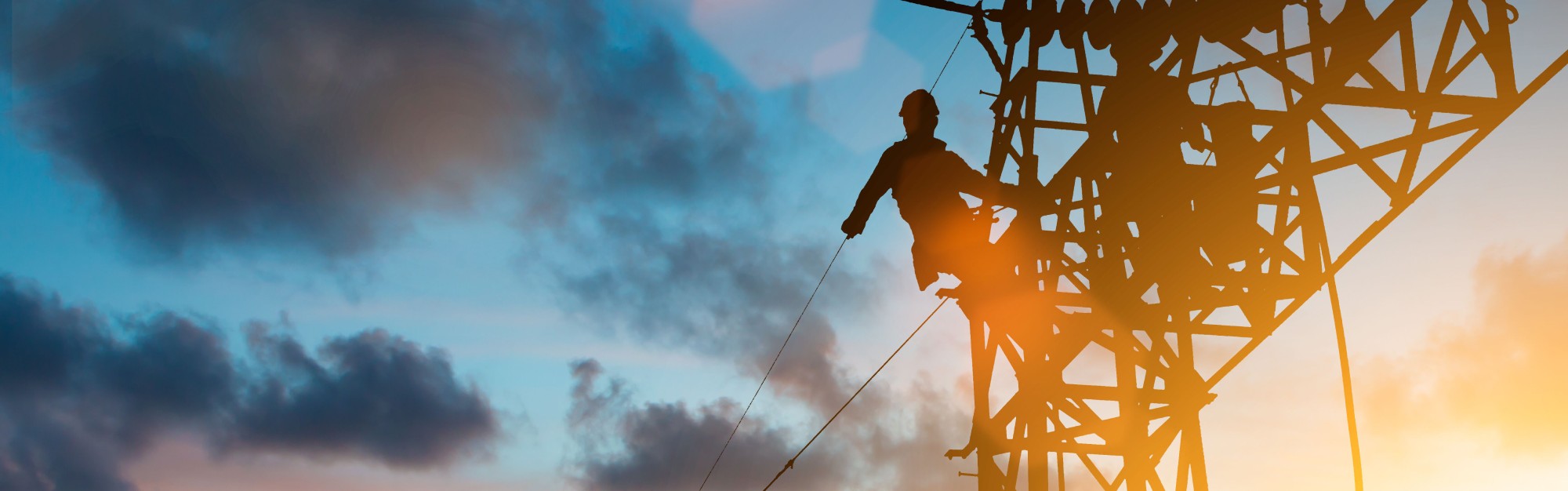 Worker on an electric pylon in the sunset